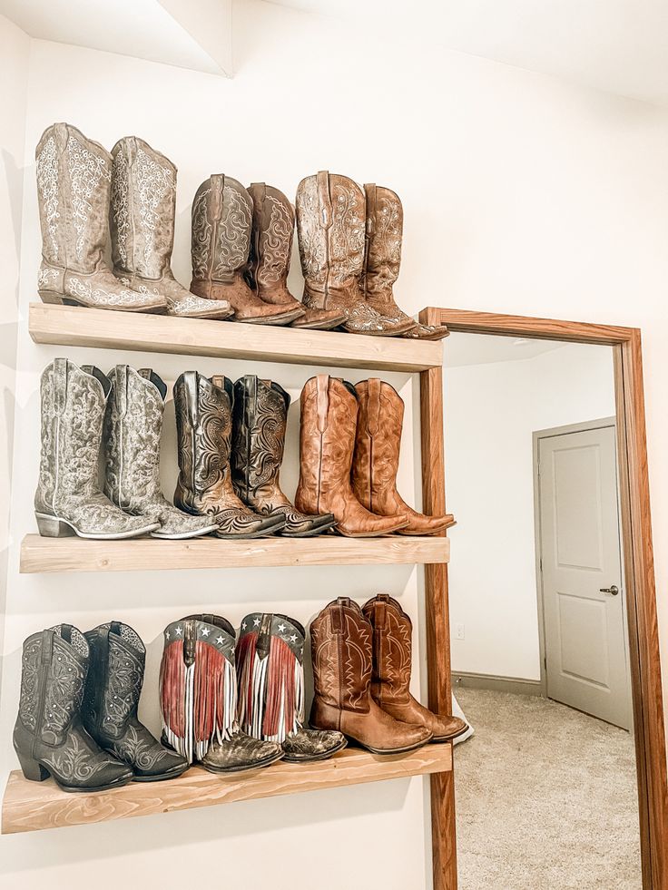 several pairs of cowboy boots are lined up on shelves in a room with a door