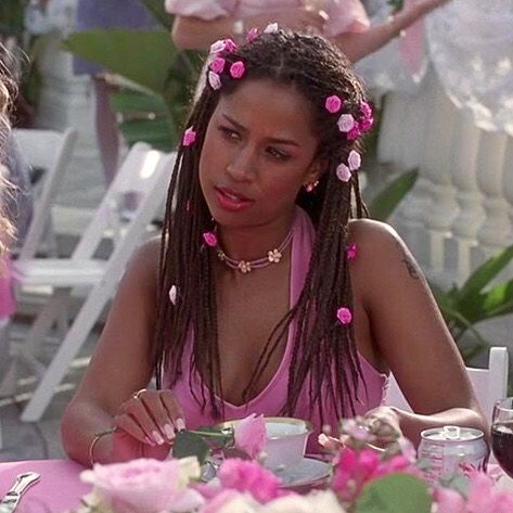 a woman sitting at a table with pink flowers in her hair