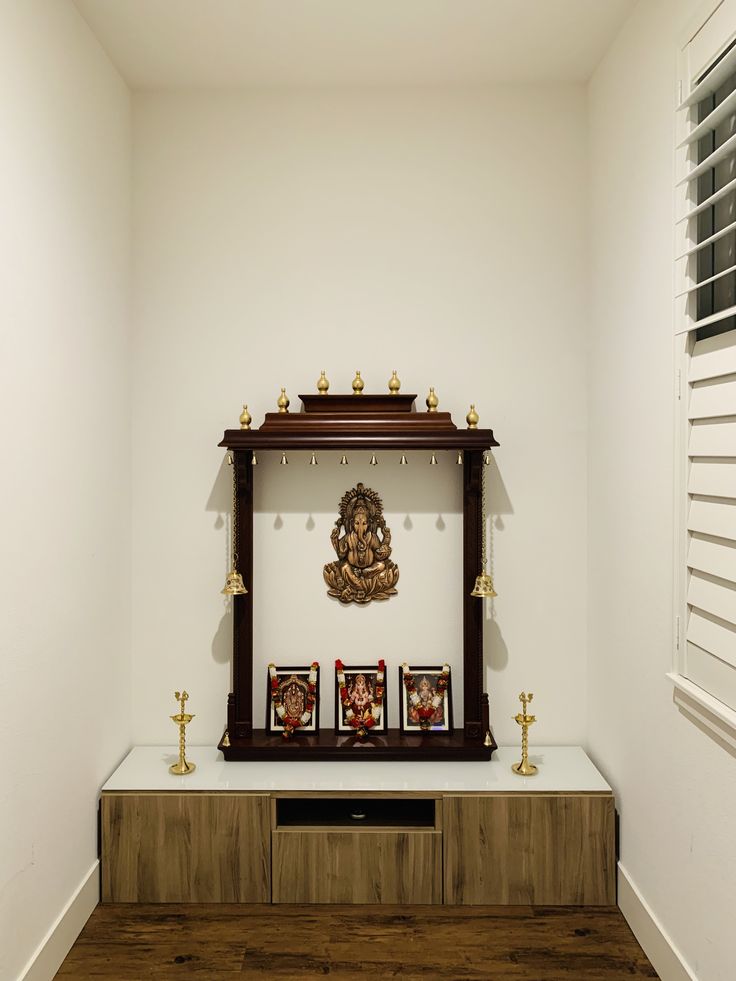 a wooden shelf with pictures on it next to a window in a white walled room