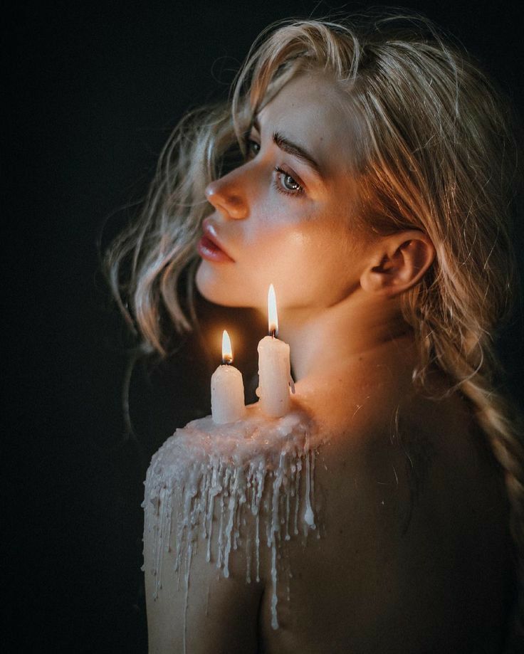 a woman holding two candles in front of her face with icing on the body