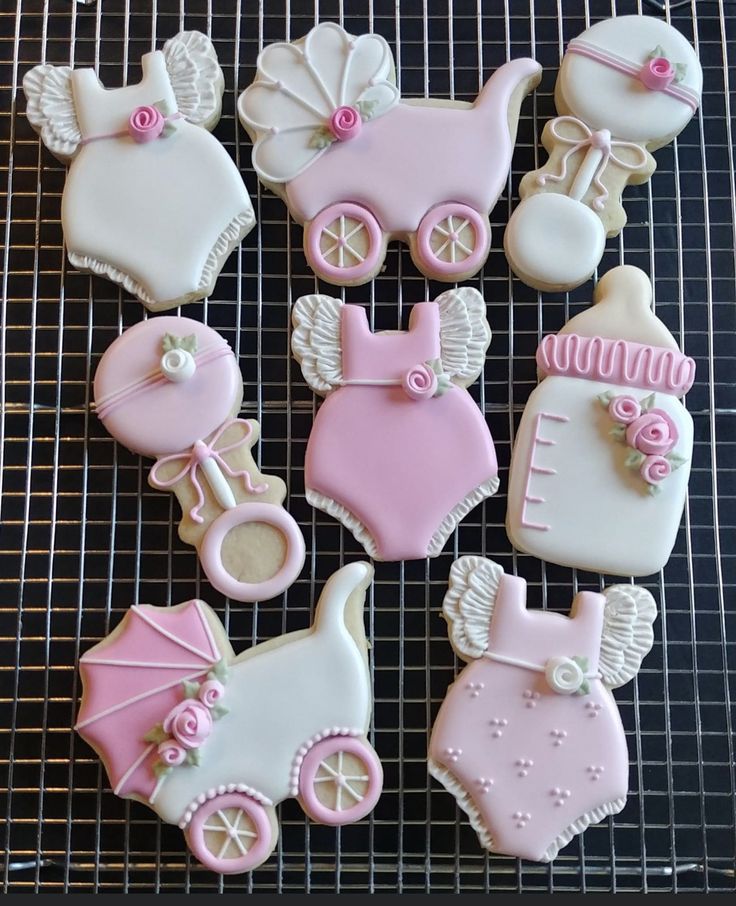 baby shower cookies decorated with pink and white icing on a wire cooling rack,