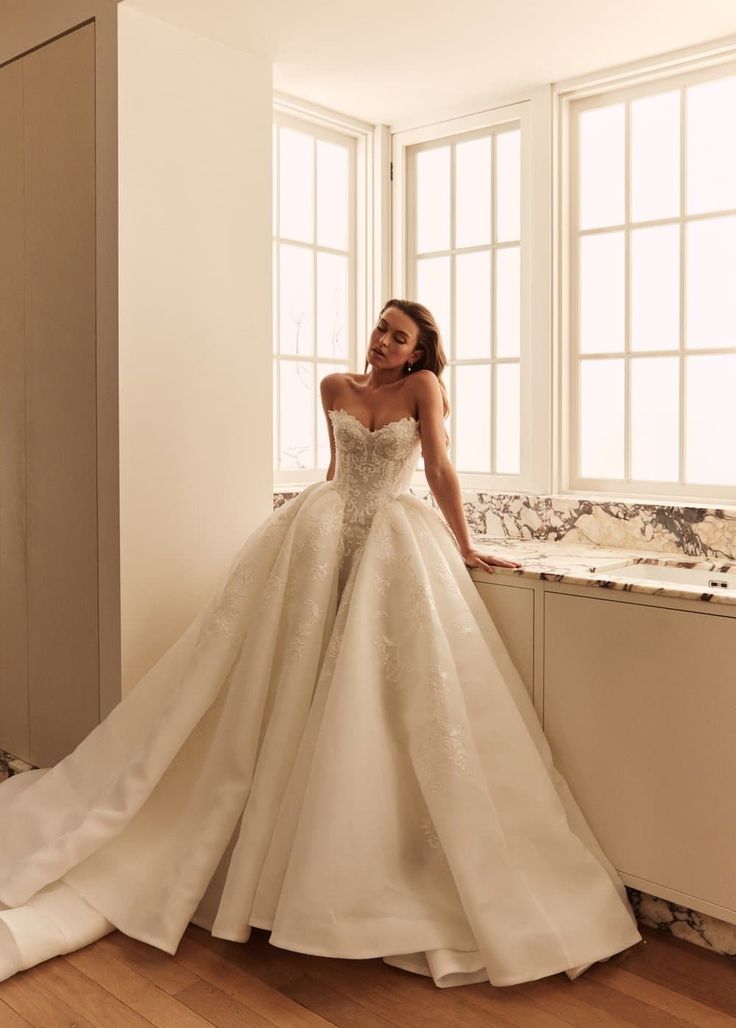 a woman in a wedding dress leaning against a window