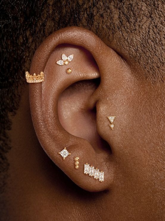 a close up of a person's ear with gold and diamond studs on it