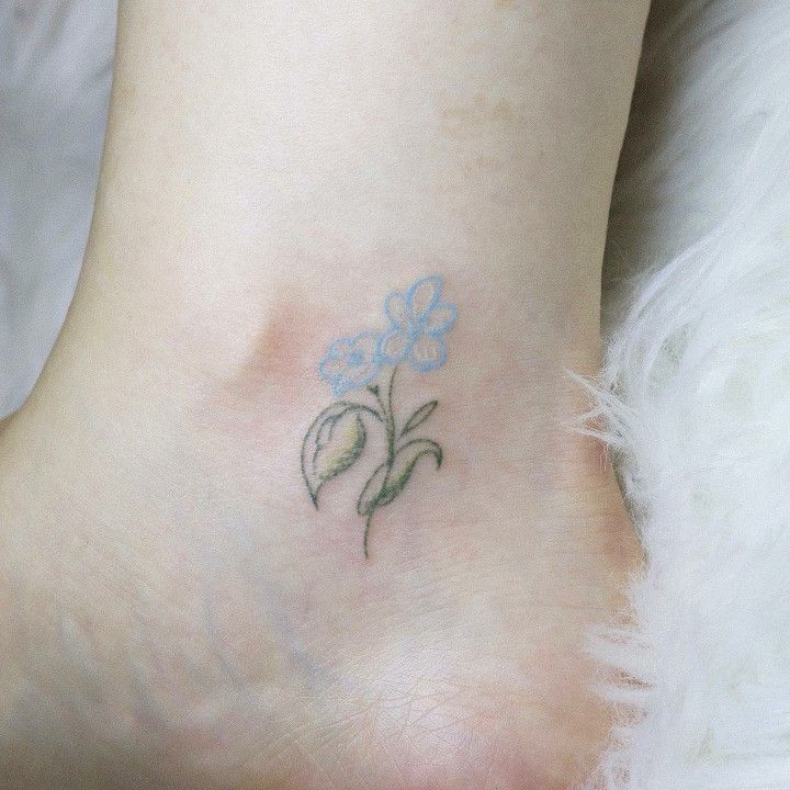 a small blue flower tattoo on the ankle