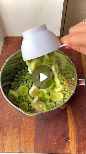 a person using a knife to cut up green beans in a pot on a wooden table