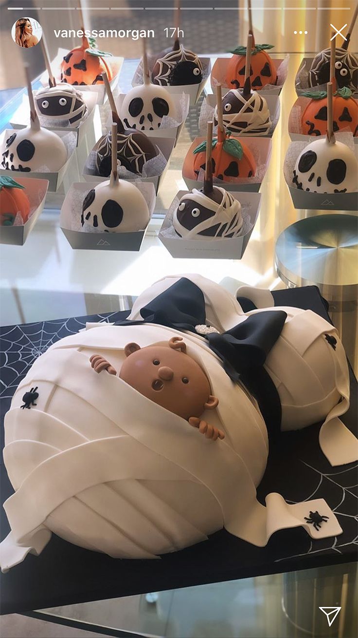 there is a cake that looks like a baby in a crib with skulls and pumpkins on it