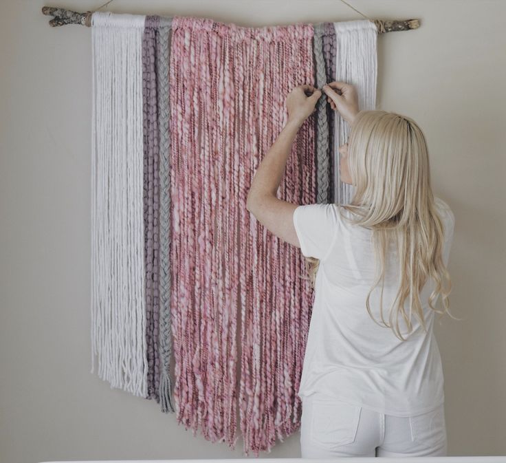 a woman is working on a wall hanging project with yarn and wood dows in front of her