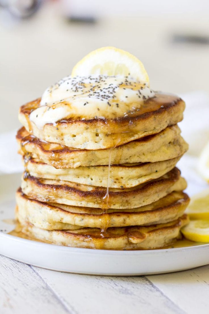 a stack of pancakes topped with lemon slices and poppy seed sprinkled on top