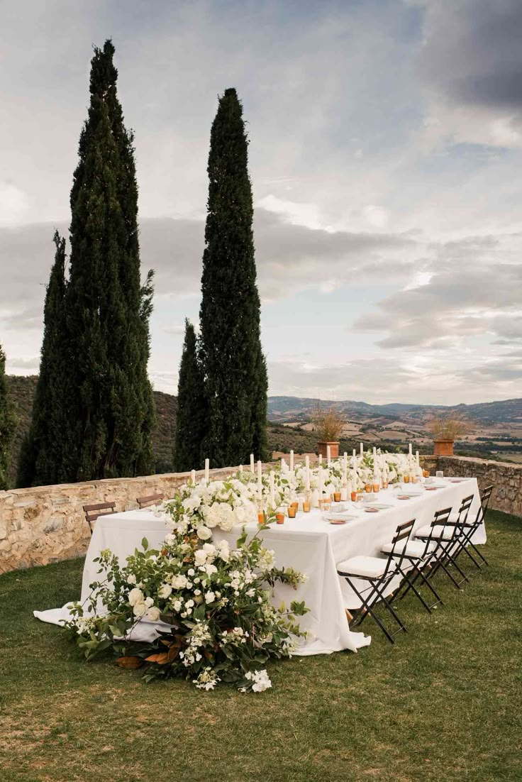 an outdoor table set up with flowers and candles for a formal dinner in the countryside