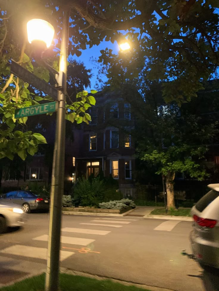 a street light sitting on the side of a road next to a car parked in front of it