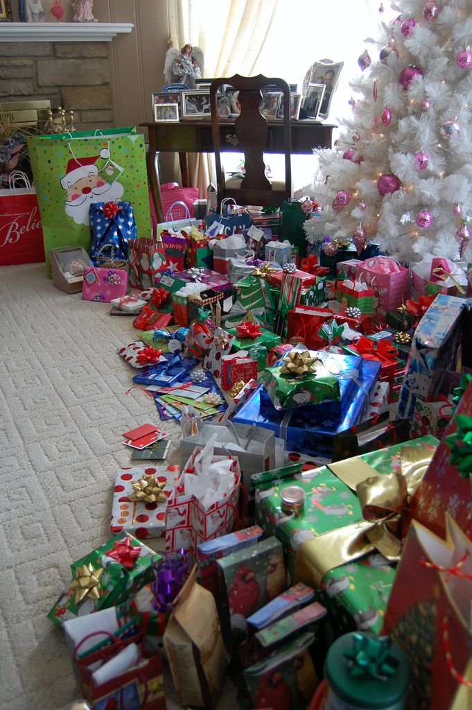 a room filled with lots of presents under a christmas tree next to a white christmas tree