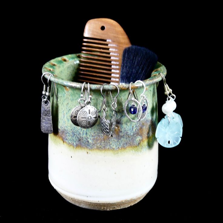 a hair brush and some charms in a cup