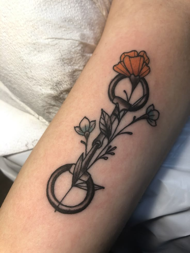 a tattoo with scissors and flowers on the arm