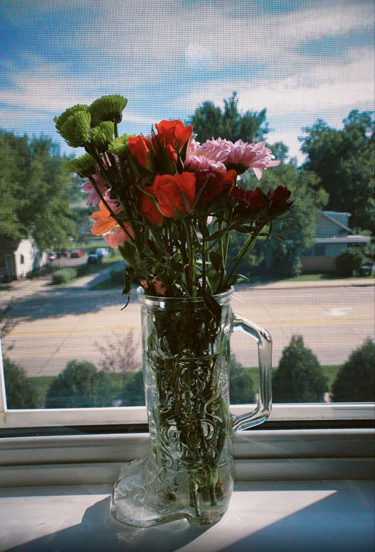 a vase filled with flowers sitting on top of a window sill