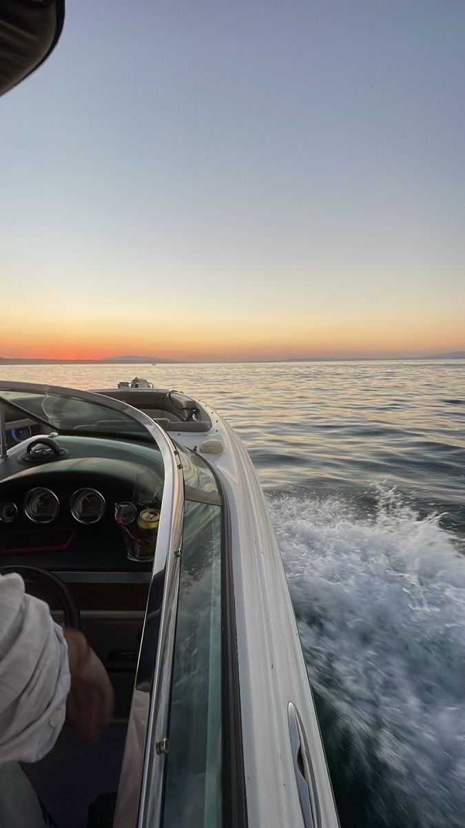 a person driving a boat in the ocean at sunset