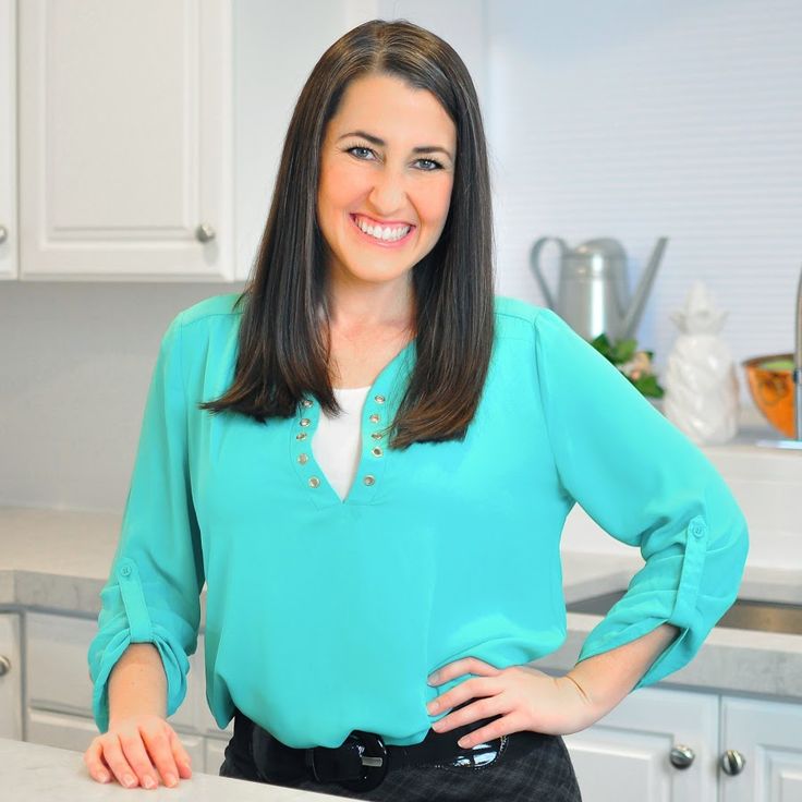 a woman standing in a kitchen with her hands on her hips and smiling at the camera