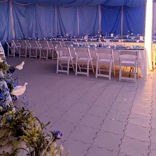 a table set up for an event with blue and white flowers in the foreground