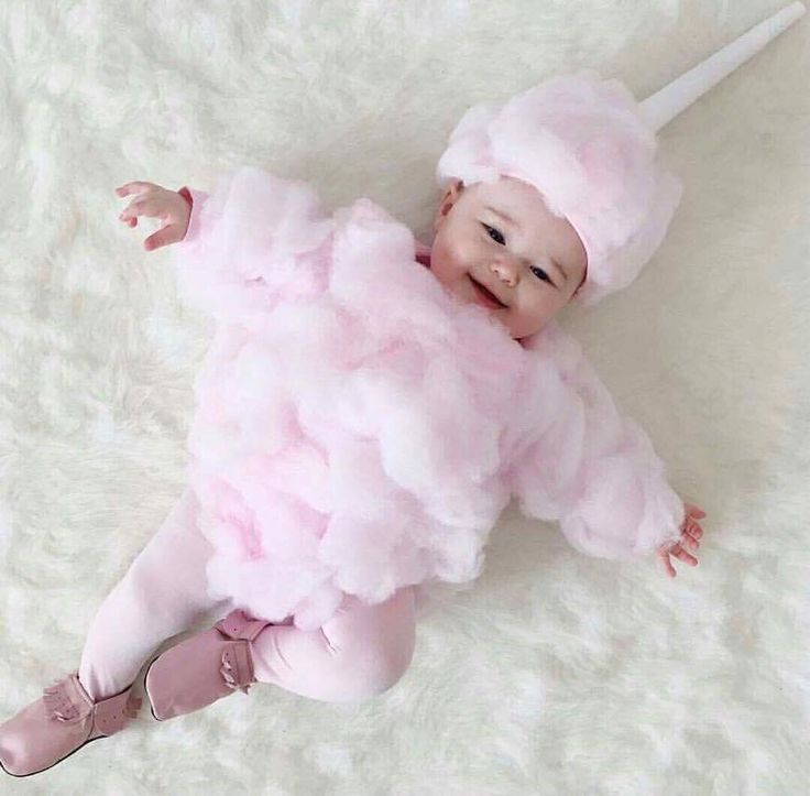 a baby wearing a pink outfit and holding a toothbrush