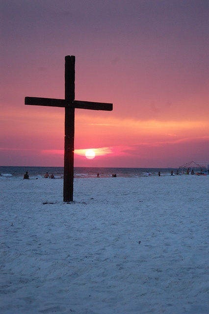 a cross in the sand at sunset