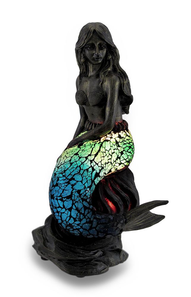 a statue of a mermaid sitting on top of a blue, green and yellow fish