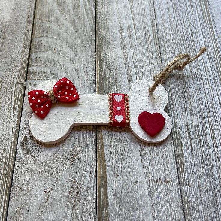 a wooden dog ornament with red hearts and a bow on it's collar