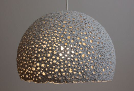 a gray and gold colored light hanging from a ceiling fixture with metal dots on it