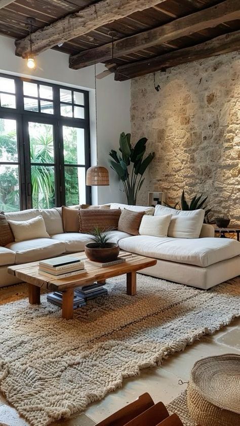 a living room filled with furniture and a stone wall behind the couch is a large window