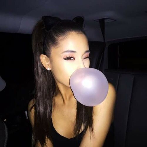 a woman blowing a bubble into her mouth in the back seat of a car at night