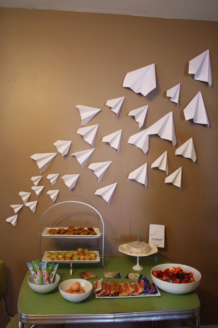 a buffet table with paper airplanes hanging from the wall and plates of food on it