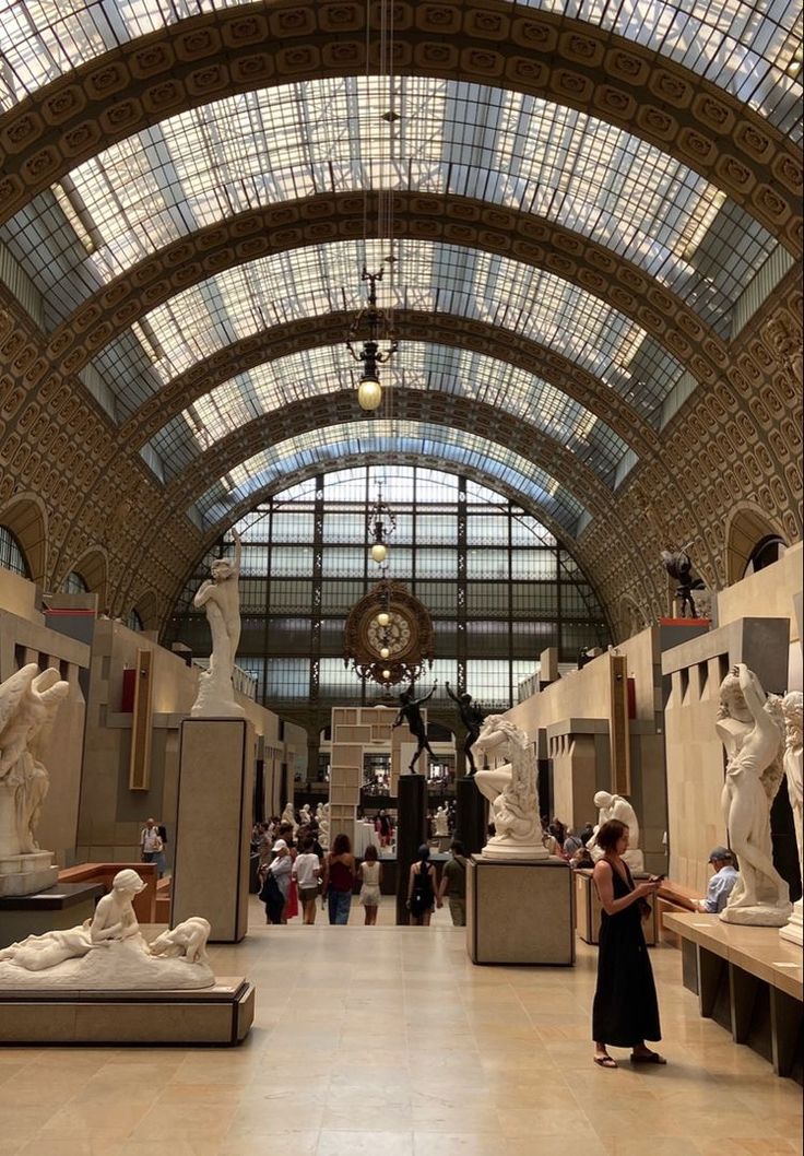 the inside of a museum with many statues and people looking at them in glass ceilings