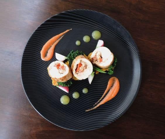 a black plate topped with food on top of a wooden table