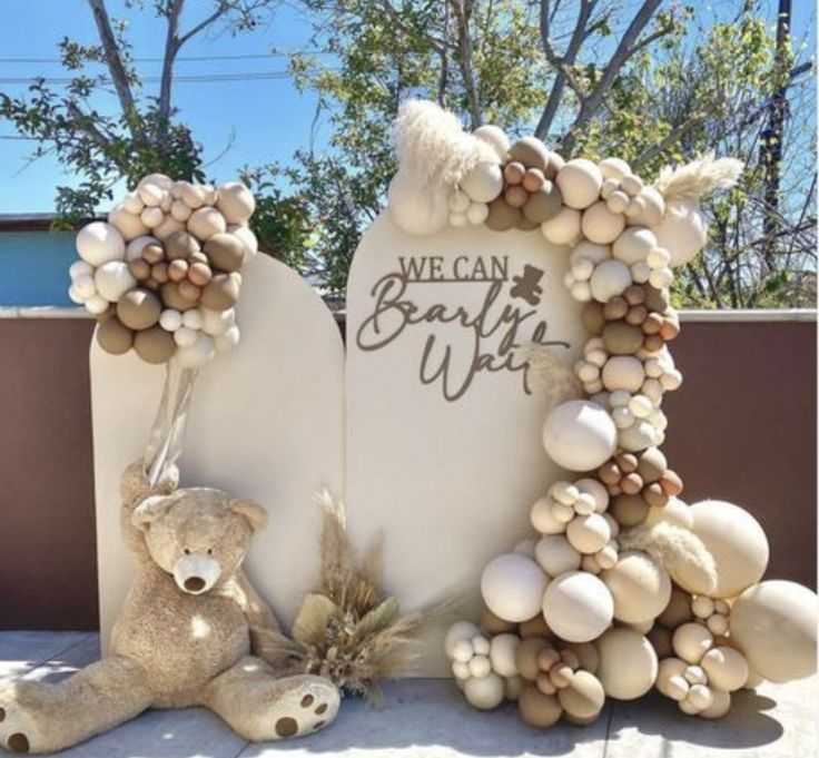 a teddy bear sitting in front of a stone sign with shells and seashells on it