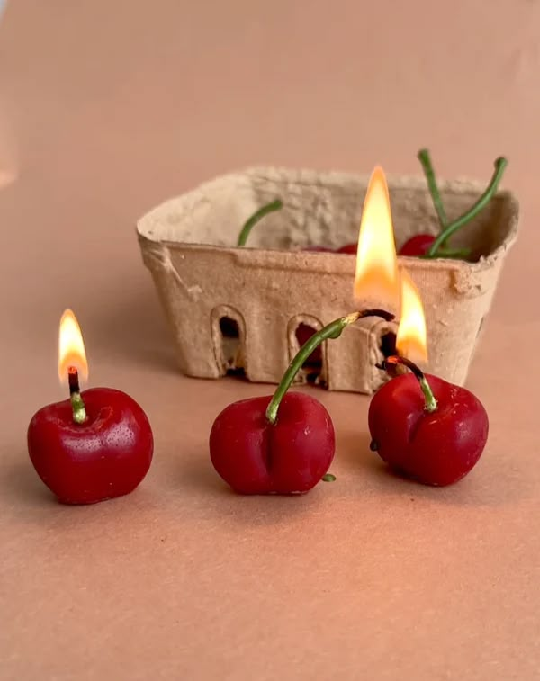 three cherries are sitting next to two candles