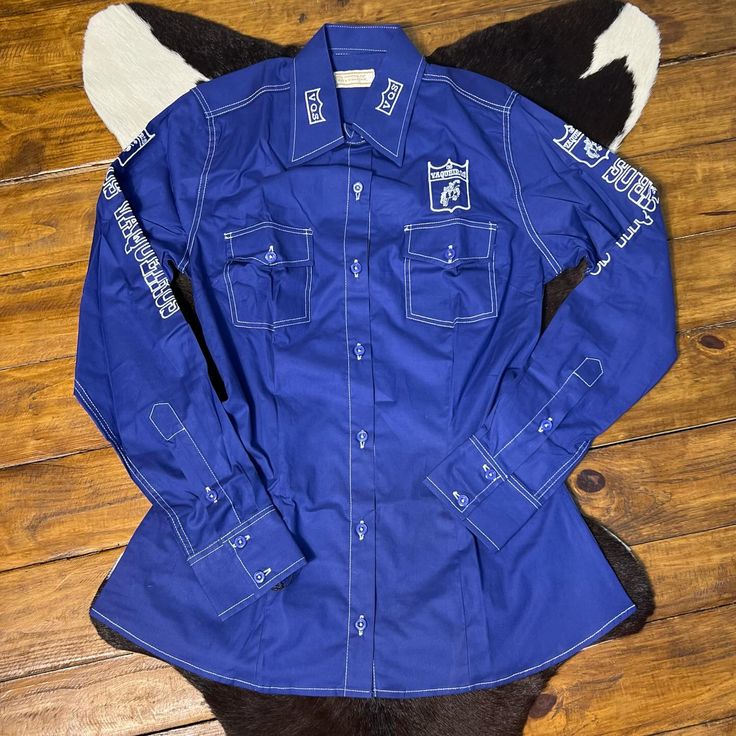 a blue shirt with white patches on it sitting on top of a hard wood floor