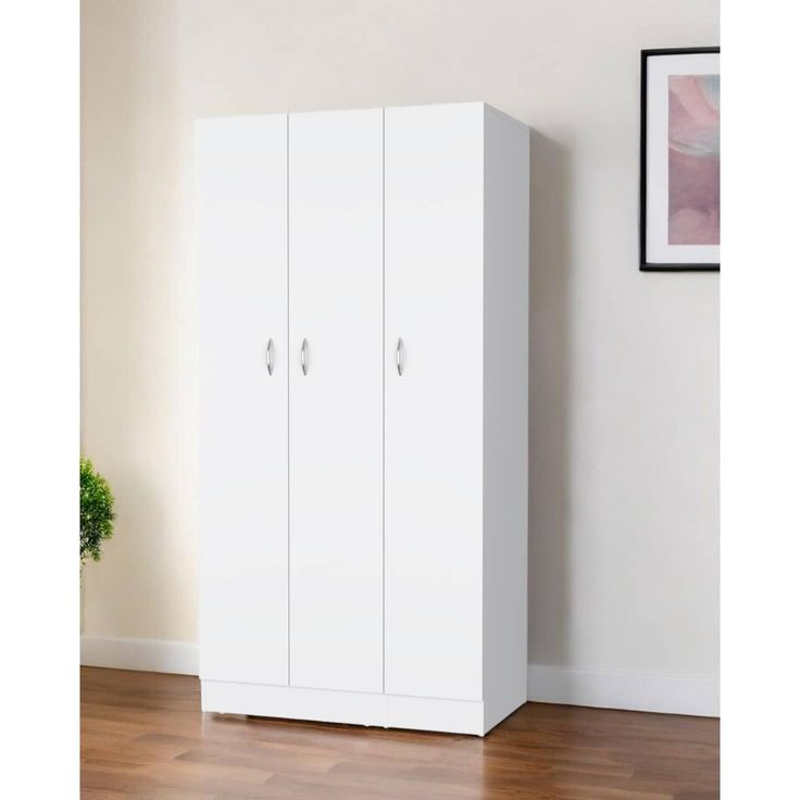 a white cabinet sitting on top of a hard wood floor next to a potted plant