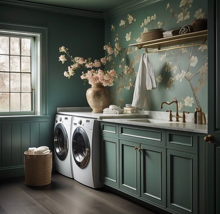 a washer and dryer in a room with green walls, flowers on the wall