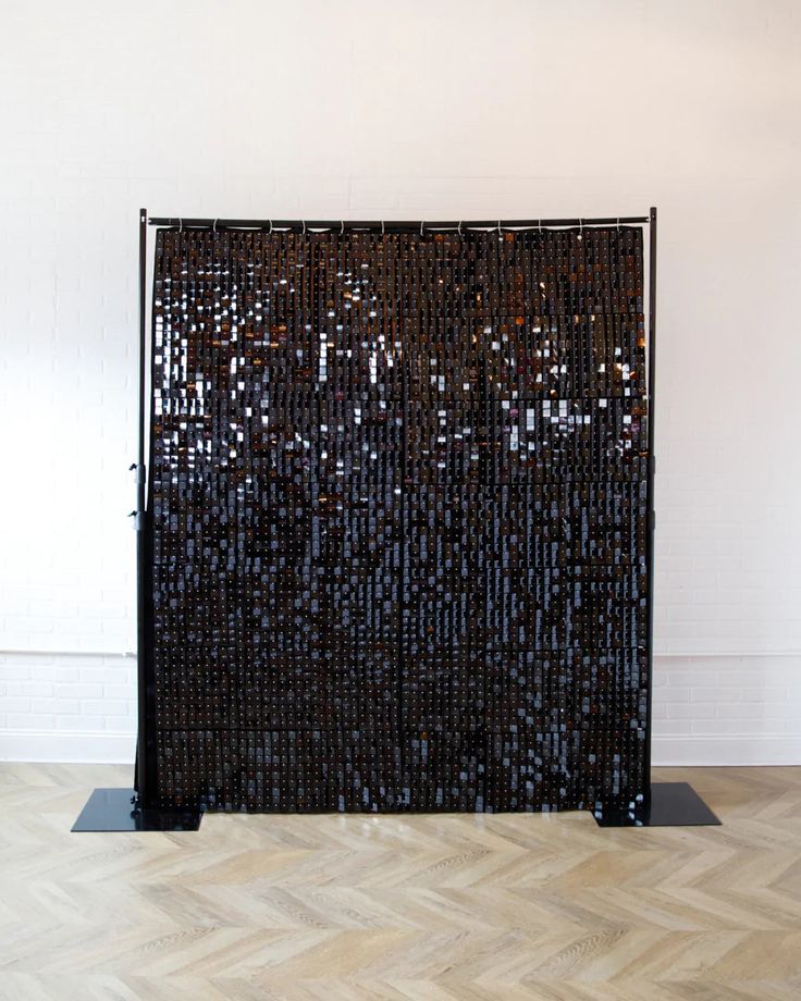 a large black sculpture sitting on top of a wooden floor next to a white wall