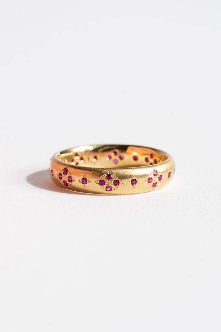 two gold wedding bands with pink flowers on the inside of each band, set against a white background