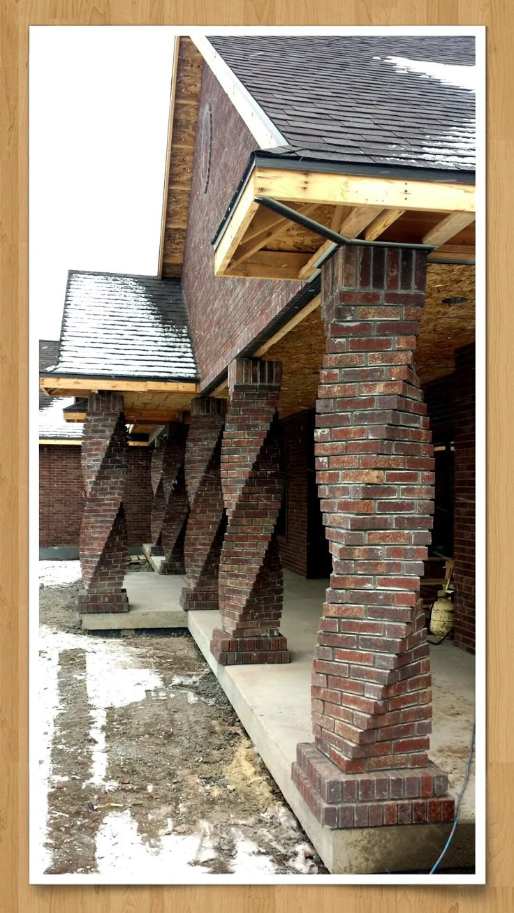 an old brick building with columns and roofing on the outside, in front of a wooden frame