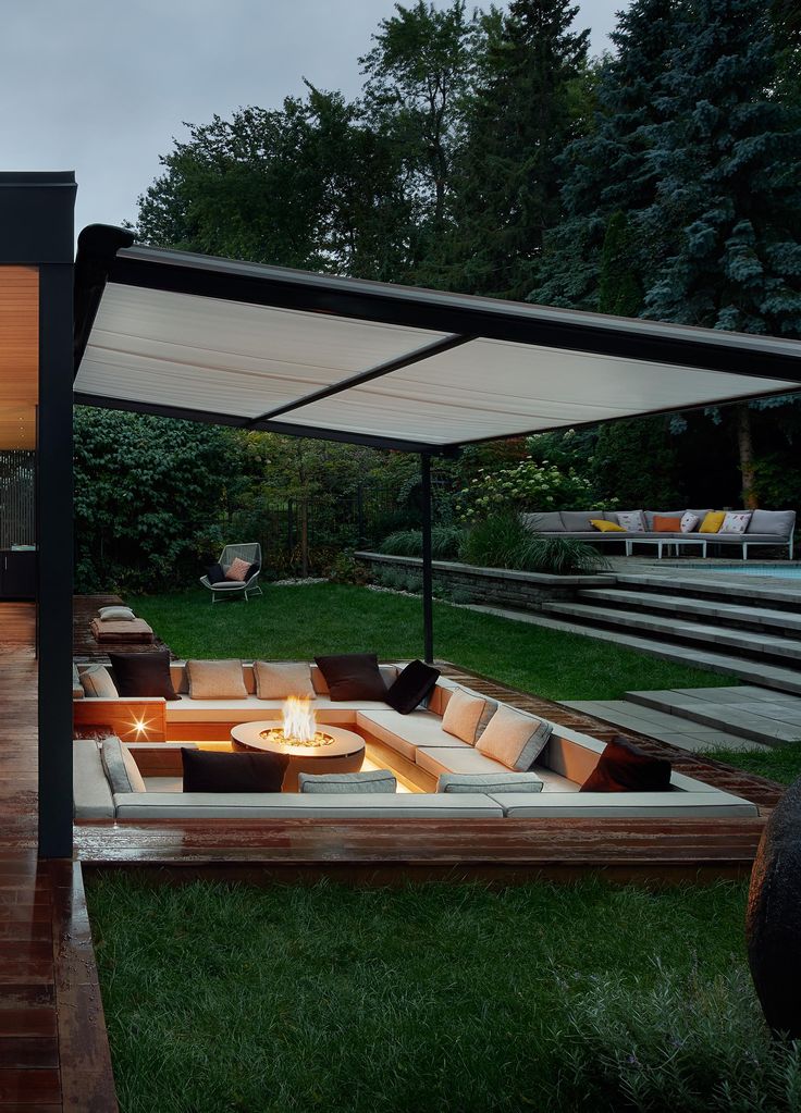 an outdoor living area with couches and fire pit in the middle of it at night