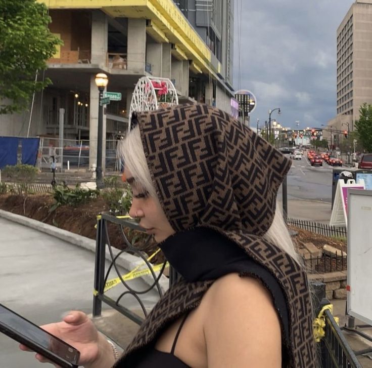 a woman with white hair wearing a brown and black scarf looking at her cell phone