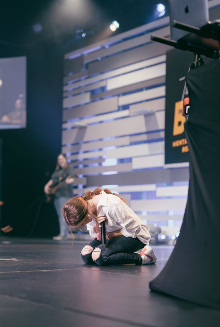 a woman kneeling down on the ground in front of a microphone