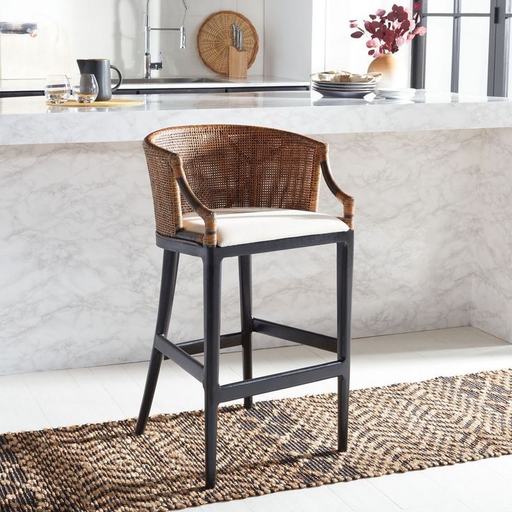 a wicker bar stool sits in front of a marble countertop with an area rug on the floor