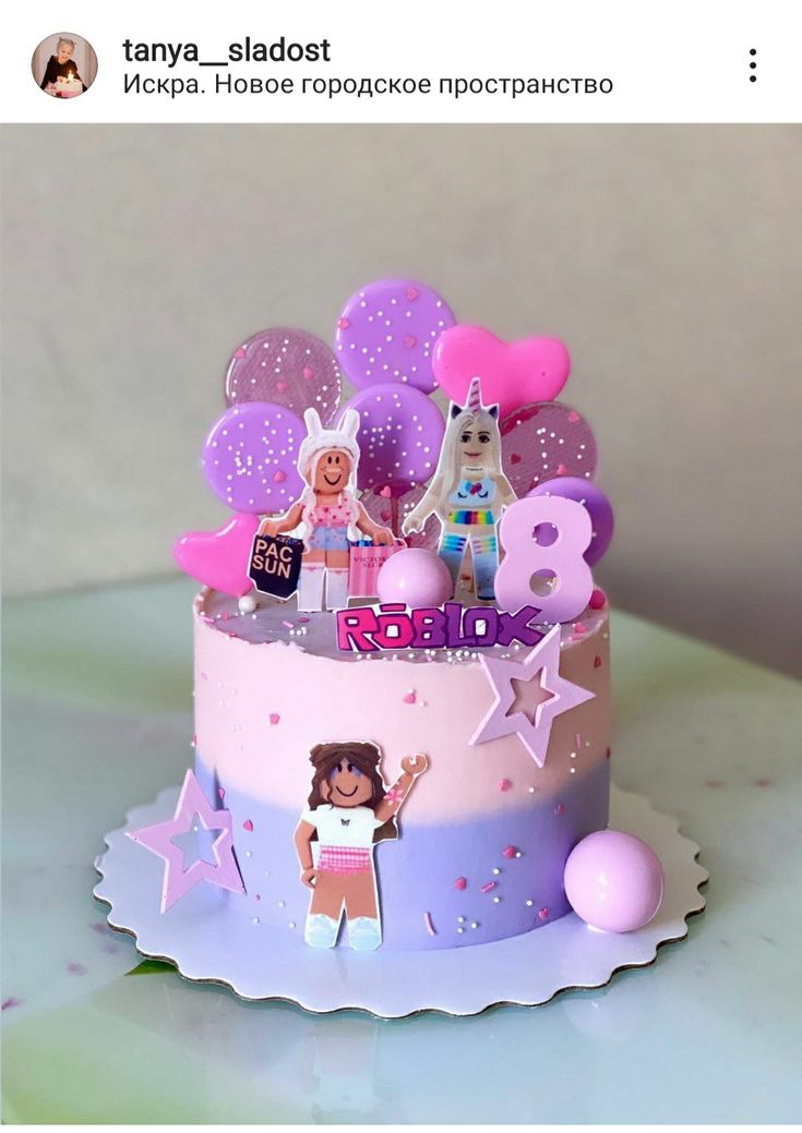 a pink and purple birthday cake with decorations on it's top, sitting on a table