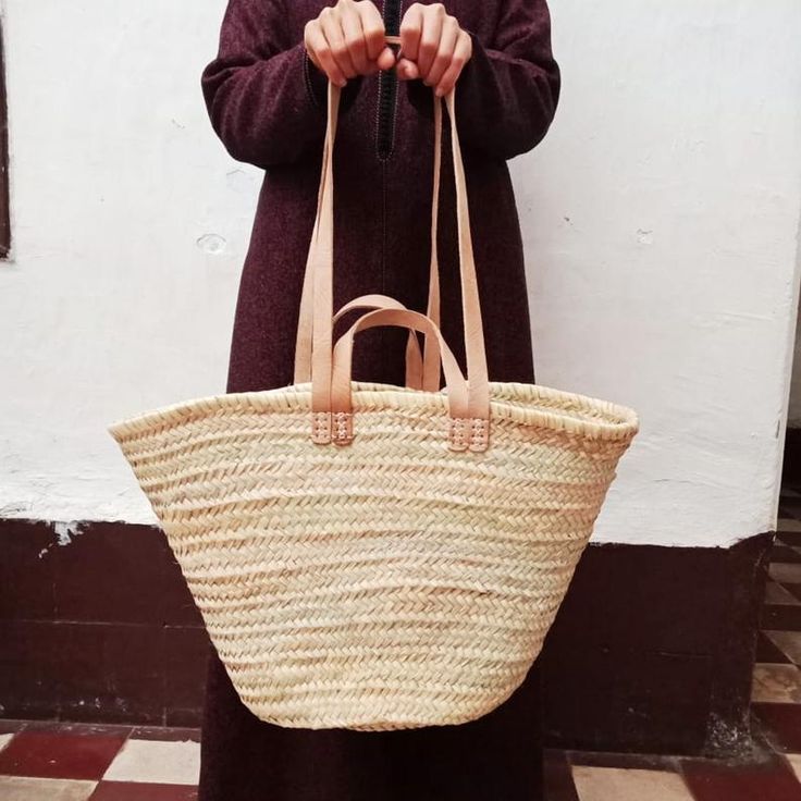 a woman is holding a large woven bag