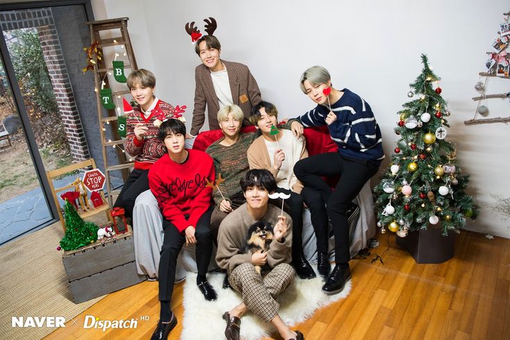 a group of people sitting next to each other in front of a christmas tree