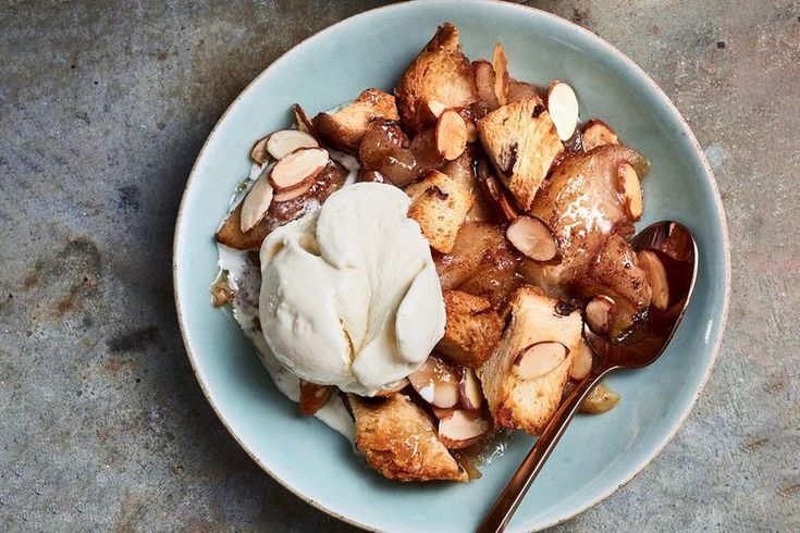 a bowl filled with dessert and ice cream on top of a stone counter next to a spoon