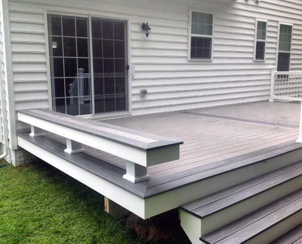 a deck with steps leading up to the front door and windows on the side of a house