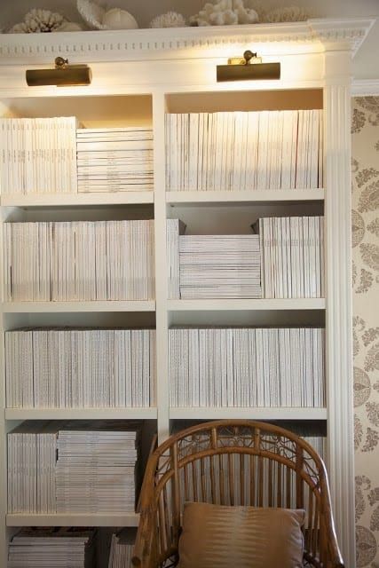 a chair sitting in front of a bookshelf filled with lots of white books