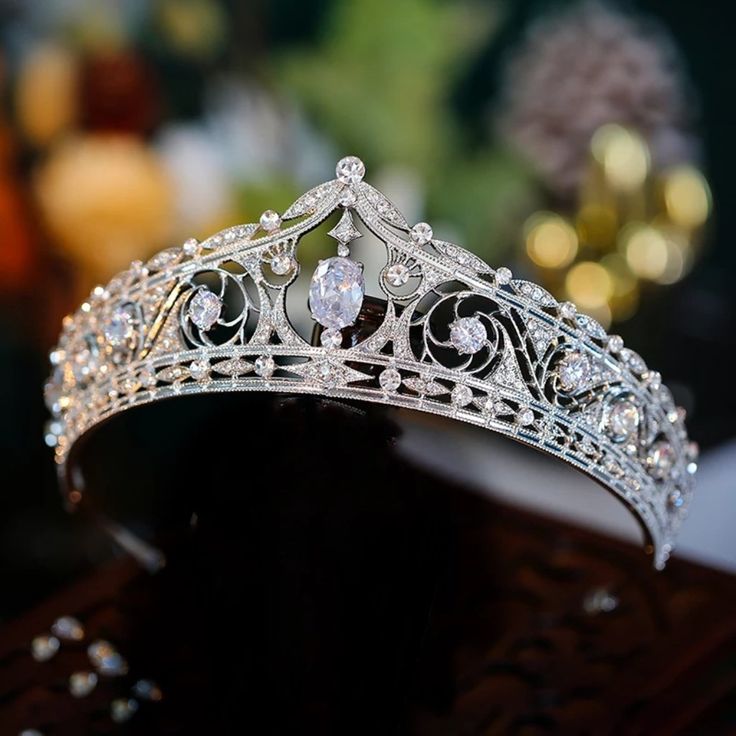 a tiara is displayed on a black stand with other items in the back ground